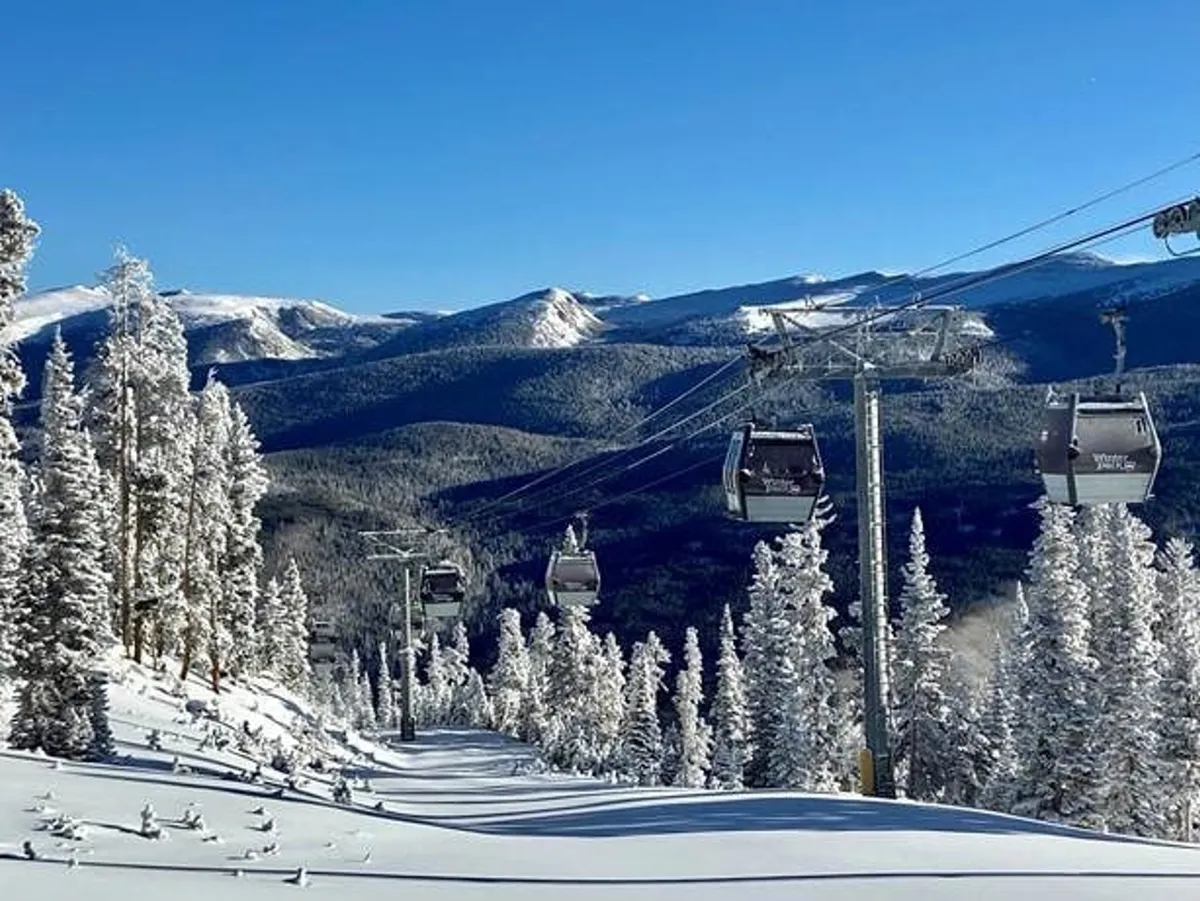 A dynamic winter scene featuring gondola lifts ascending above snow-covered slopes, surrounded by majestic mountains and pine trees. The lively atmosphere invites thoughts of skiing, snowboarding, and scenic rides, capturing the excitement and adventure of the Winter Park Resort area.
