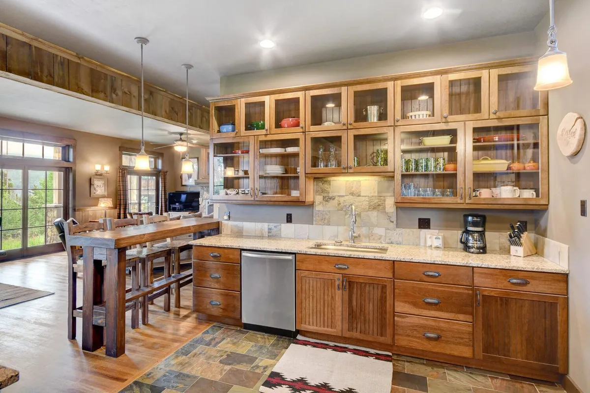 A chef’s kitchen with a central island, gleaming stainless steel appliances, glass-front cabinets, and inviting wood detailing. The space feels ready for cooking together, entertaining guests, and enjoying morning coffee while taking in the view through large windows.