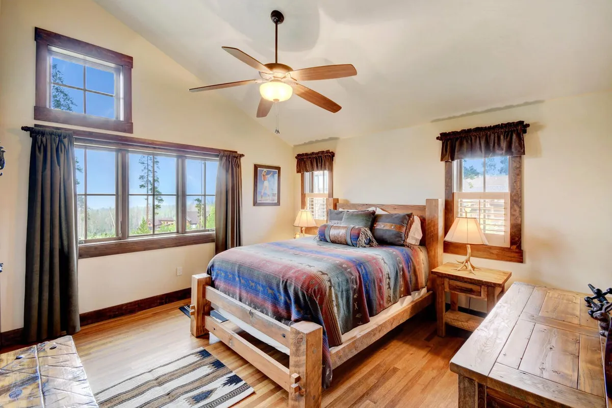 A comfortable bedroom with a wooden bed, decorative pillows, and large windows that frame scenic outdoor views. The décor is warm and inviting, with soft bedding and cozy lighting, creating a perfect sanctuary for relaxation.